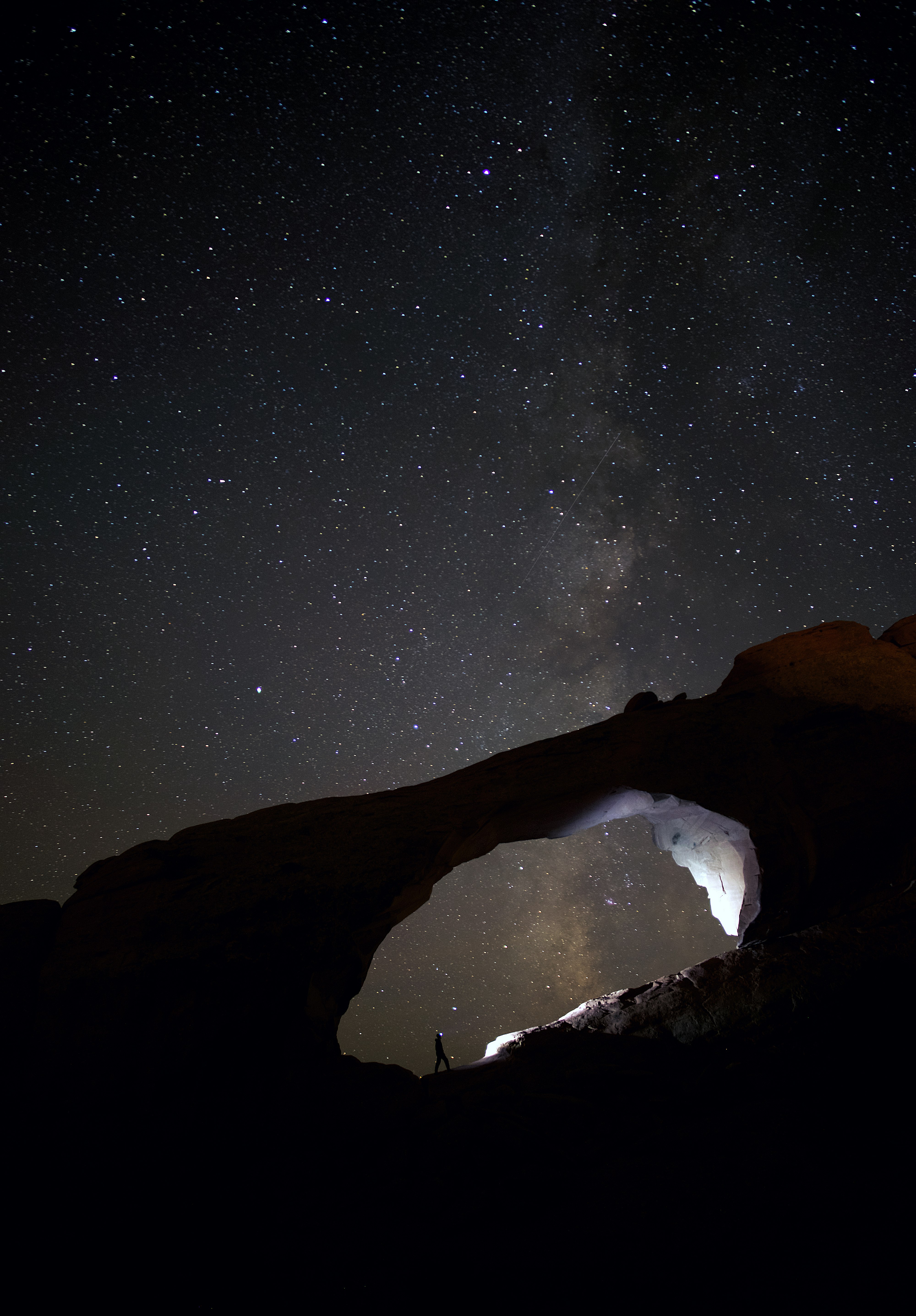 silhouette photo of person stand on rocks during nighttime